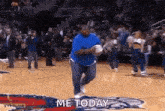 a man in a blue shirt is running on a basketball court with the words `` me today '' written on the ground .