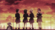 a group of girls are standing on a balcony looking at a sunset