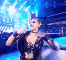 a woman is standing in a wrestling ring with her arms outstretched .