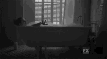 a black and white photo of a person in a bathtub with fx written on the bottom right
