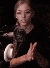 a woman wearing glasses and headphones is clapping her hands in front of a microphone