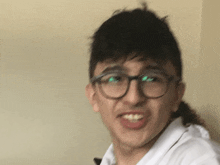 a young man wearing glasses and a white shirt is making a funny face