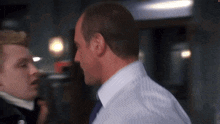 a man in a white shirt and tie is talking to another man in a black shirt and tie .