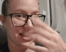 a woman wearing glasses is holding her nose .
