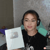 a woman wearing headphones and glasses holds up a youtube badge