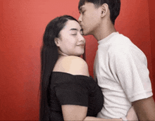 a man kisses a woman on the cheek while she looks on