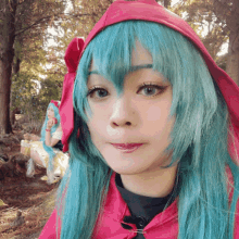 a woman with green hair and a red hood