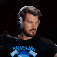 a man with a beard is wearing headphones and a t-shirt with a shark on it .