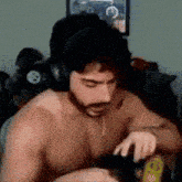 a shirtless man wearing headphones is sitting in a room .