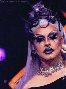 a drag queen with purple hair and a crown on her head looks at the camera with the words vonxodd tumblr above her