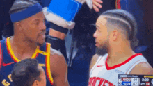 two basketball players are talking to each other on the court .