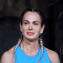 a woman with braids is wearing a blue tank top and earrings