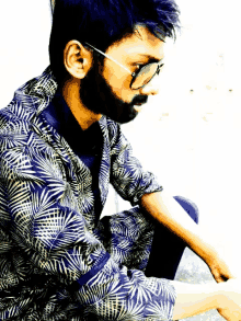 a man with glasses and a beard is wearing a blue and white shirt
