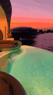 a swimming pool with a boat in the background and a sunset in the background