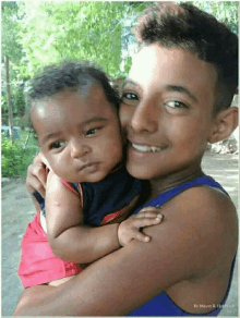 a boy is holding a baby in his arms and smiling