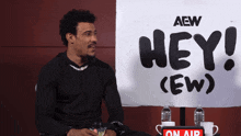 a man is sitting in front of a sign that says hey
