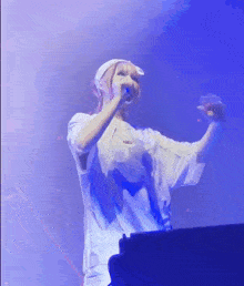 a woman singing into a microphone while wearing a white hat