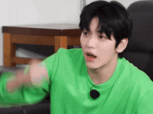 a young man in a green shirt is sitting in a chair
