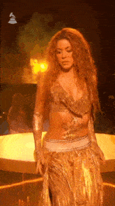 a woman in a gold dress is standing on a stage .
