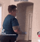 a man in a blue shirt and glasses is standing in a hallway in front of a door .