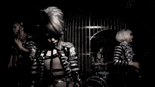 a woman in a striped outfit is standing in front of a drum set .