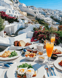 a table with plates of food and a glass of orange juice with a city in the background