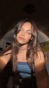 a young woman is taking a selfie in front of a rainbow in a dark room .