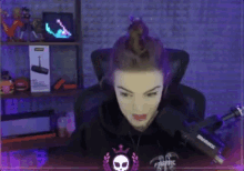 a woman is sitting in a chair in front of a microphone and looking at the camera .