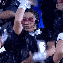 a woman wearing sunglasses and gloves is dancing in front of a star