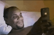 a man is laying on a bed looking at his phone