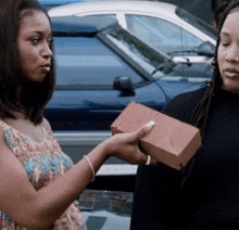 two women are standing next to each other and one is holding a red brick