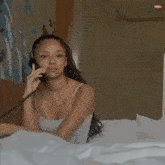 a woman is laying in bed talking on a phone with her eyes closed