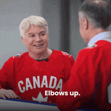 a man wearing a red canada elbows up shirt