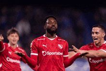 a soccer player wearing a red sportsbet jersey celebrates
