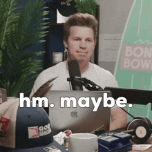 a man sitting in front of a microphone with the words hm maybe