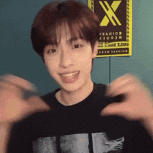 a young man wearing a black shirt with the letter x on the front