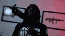 a man is holding a gun in his hand in a room with a red light behind him .