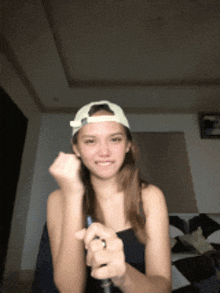 a woman wearing a white baseball cap is holding a pen in her hand