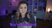 a woman is sitting in a chair with the words `` you 're the best '' on the screen .