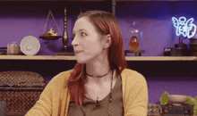 a woman sitting in front of a purple wall with a neon sign that says yes