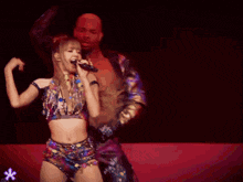 a woman is singing into a microphone while a man holds her waist