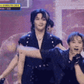 a man in a black jacket is standing next to another man in a black jacket on a stage .