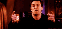 a man in a black shirt is making a funny face while holding something in his hand .