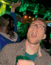 a man with glasses and a blue shirt is dancing in a club