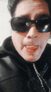 a woman wearing sunglasses and a black jacket is making a funny face