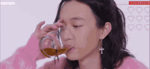 a man with long hair is drinking a glass of liquid .