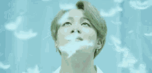 a close up of a person looking up at the sky with feathers flying around them .