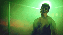 a man without a shirt is standing in a green room