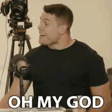 a man in a black shirt is standing in front of a microphone and making a funny face .