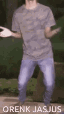 a man in a grey t-shirt and blue jeans is dancing with the words orenk jasjus below him
